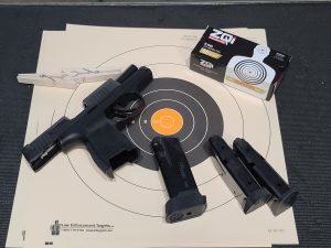 A gun and several ammunition magazines pictured at a shooting range