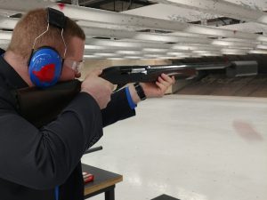 A handsome young reporter fires a shotgun equipped with a silencer