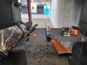 A semi-atuomatic unserialized shotgun made by Sears sits on a bench at a range / Stephen Gutowski