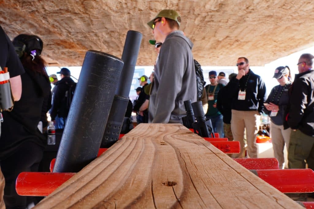 Rifles equipped with silencers sit on a rack at SHOT Show 2022's range day