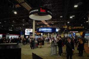 Industry members walk the convention floor under gun company signs at SHOT Show 2022 in Las Vegas, Nevada