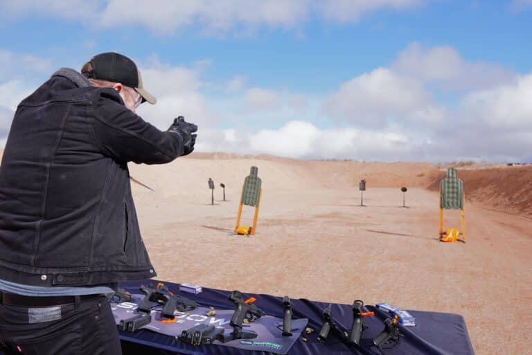 A handsome, towering man shoots at an outdoor range