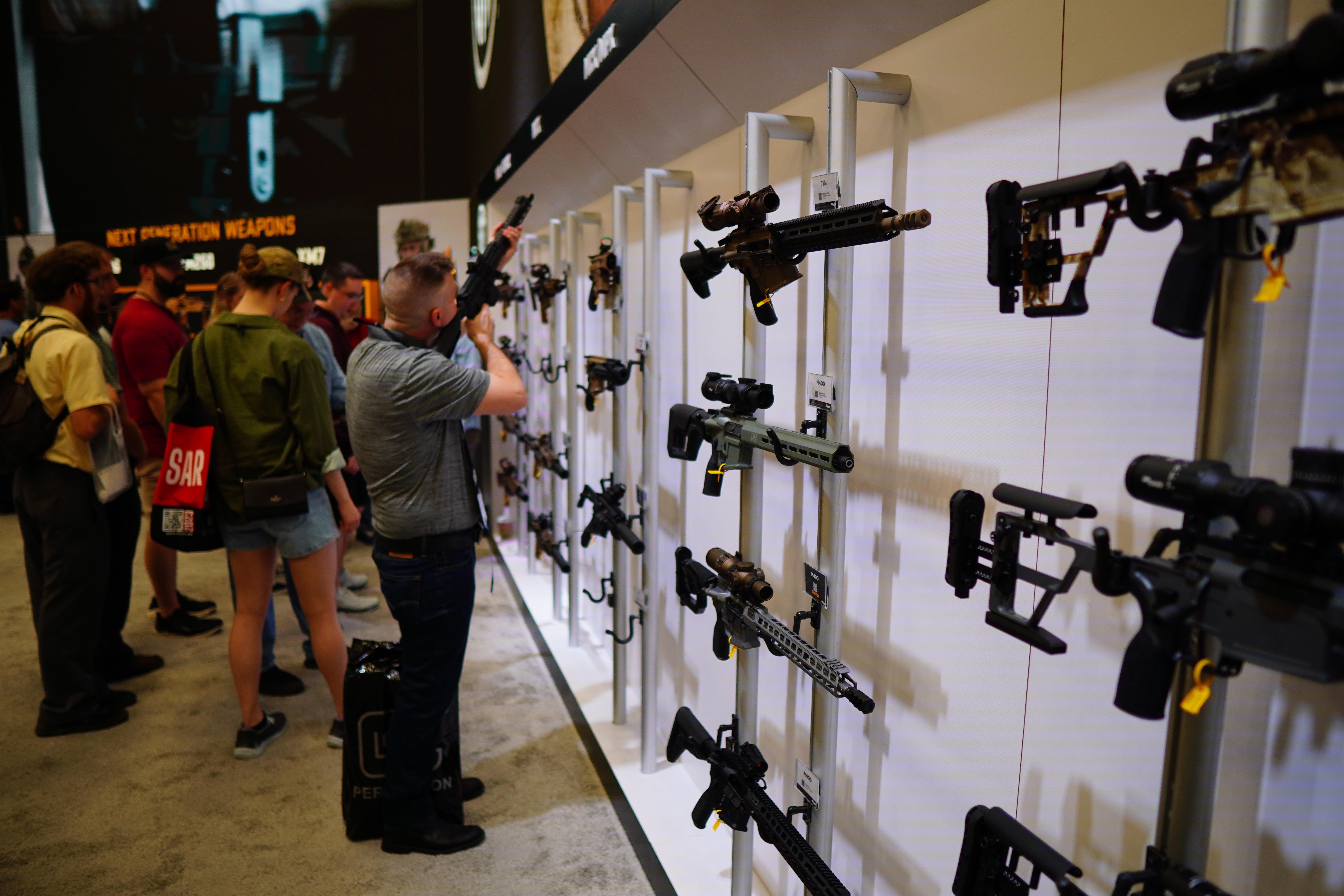 A man examines a rifle at the Sig Sauer booth during the 2023 NRA Annual Meeting