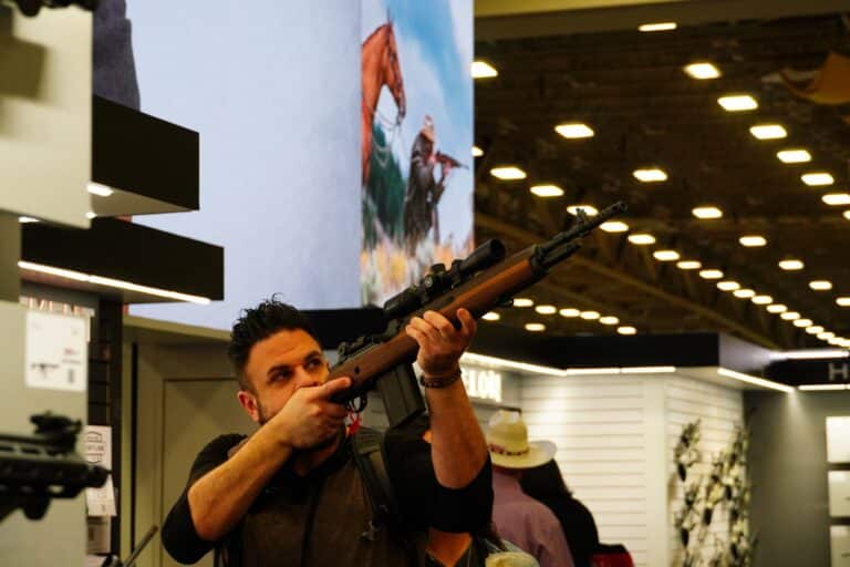 An attendee at the 2024 NRA Annual Meeting examines a rifle