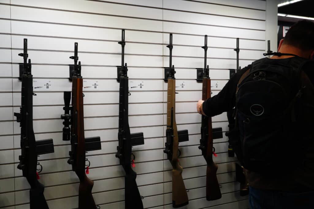 An attendee at the 2024 NRA Annual Meeting examines a rifle display