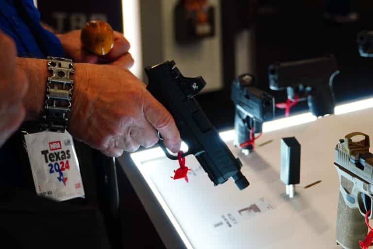 A 2024 NRA Annual Meeting attendee handles a handgun