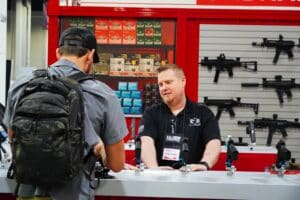 An attendee and exhibitor talk in a booth at the 2025 NRA Annual Meeting