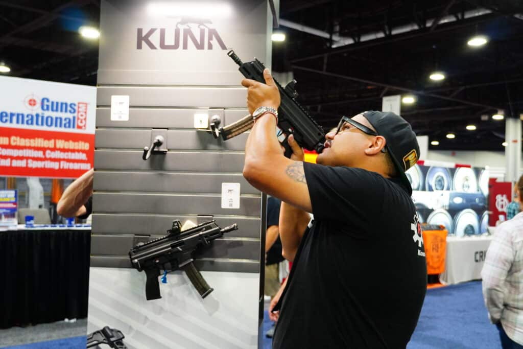 An attendee examines a firearm on the 2025 NRA Annual Meeting exhibit floor